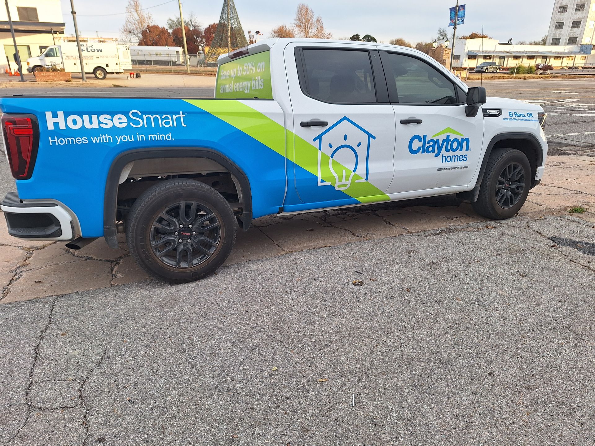 A blue and white truck with a house smart advertisement on the side is parked on the side of the road.