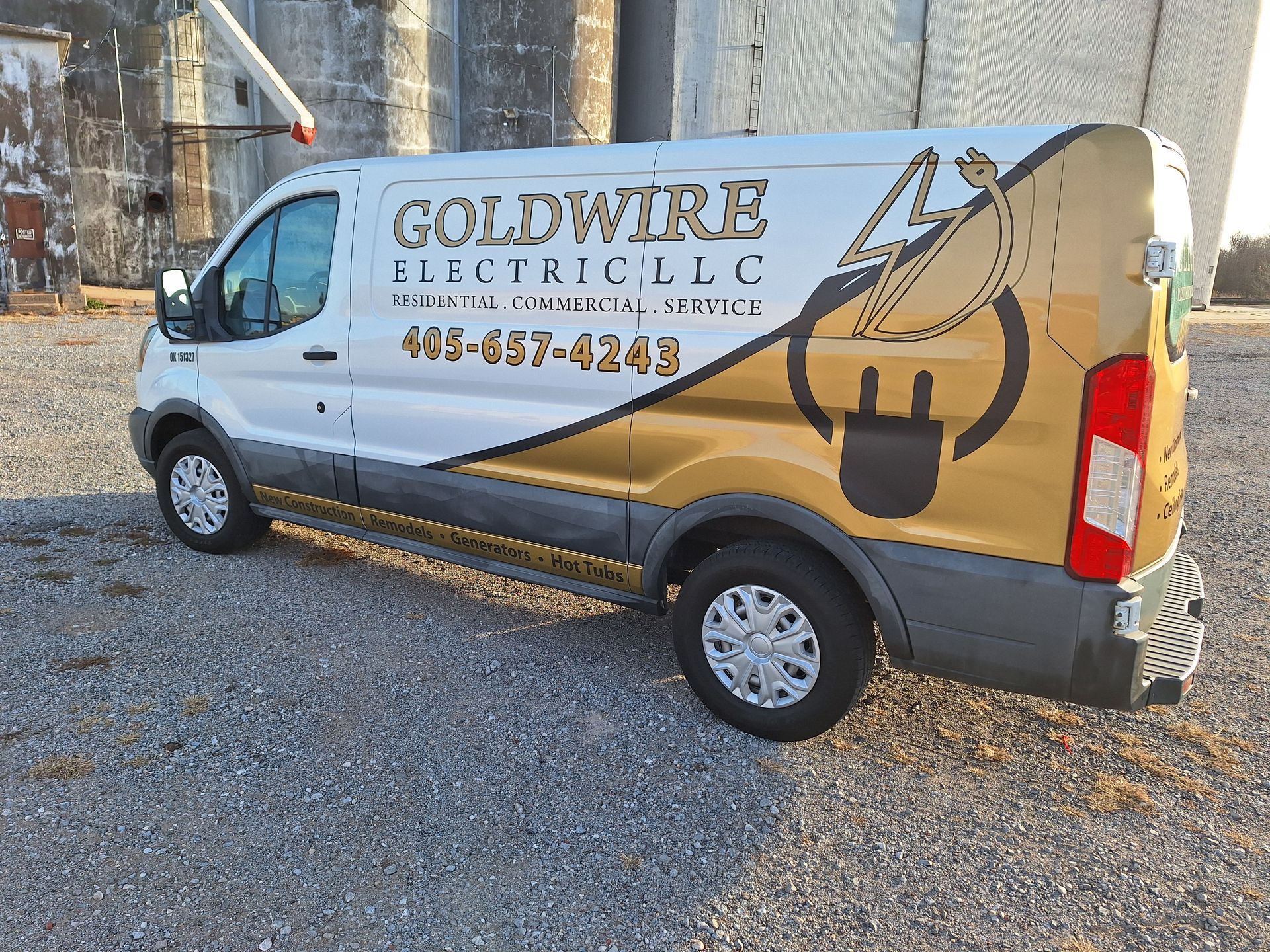 A goldwire electrical llc van is parked in a gravel lot