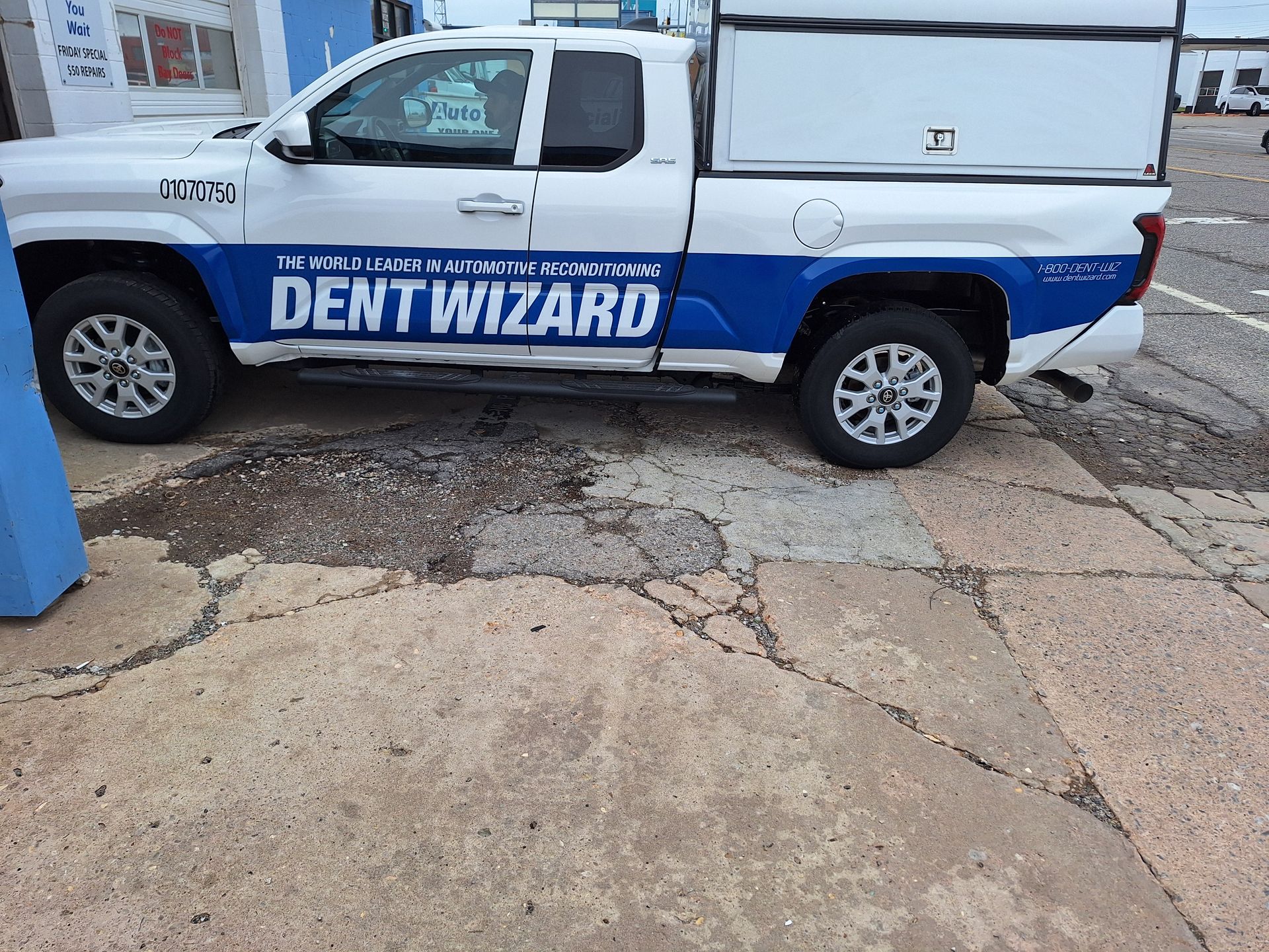 A dent wizard truck is parked in a parking lot.