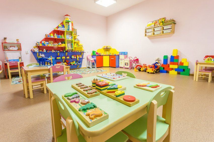 A child care room with tables and chairs and lots of toys