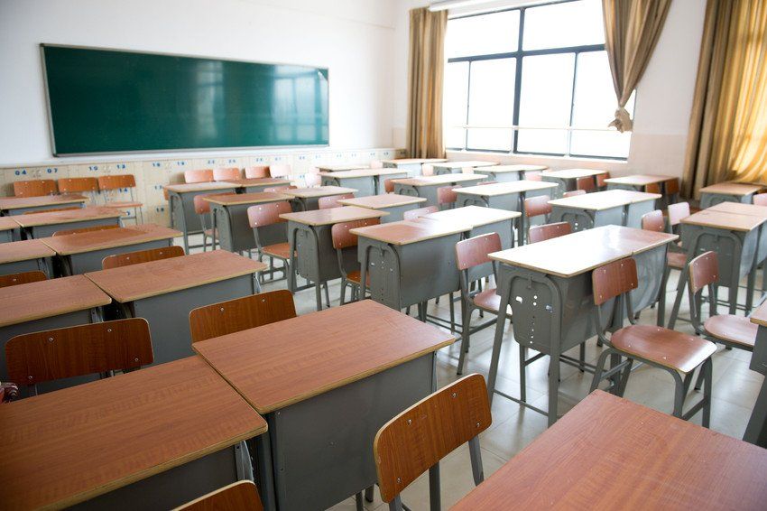 An empty classroom with wooden desks and chairs