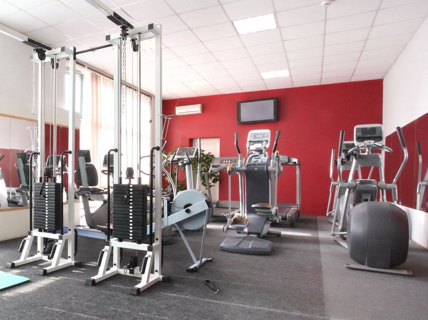 A gym with a lot of equipment and a red wall