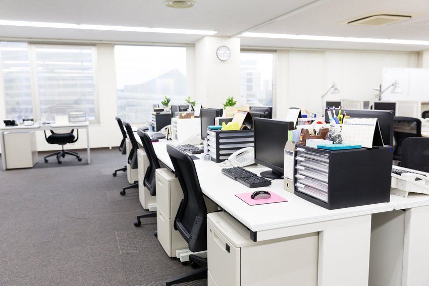 An office with a lot of desks and chairs and a clock on the wall