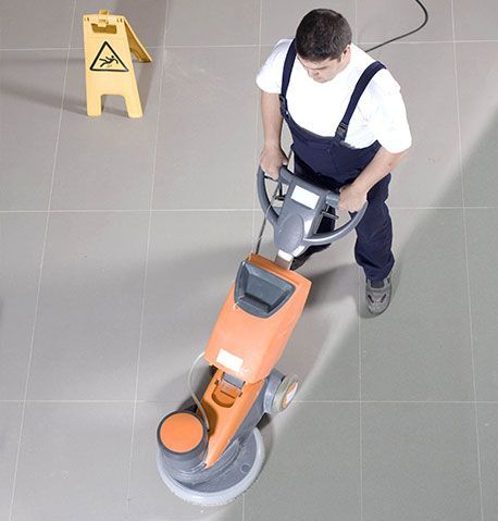 A janitor uses a machine to clean and buff the office floor