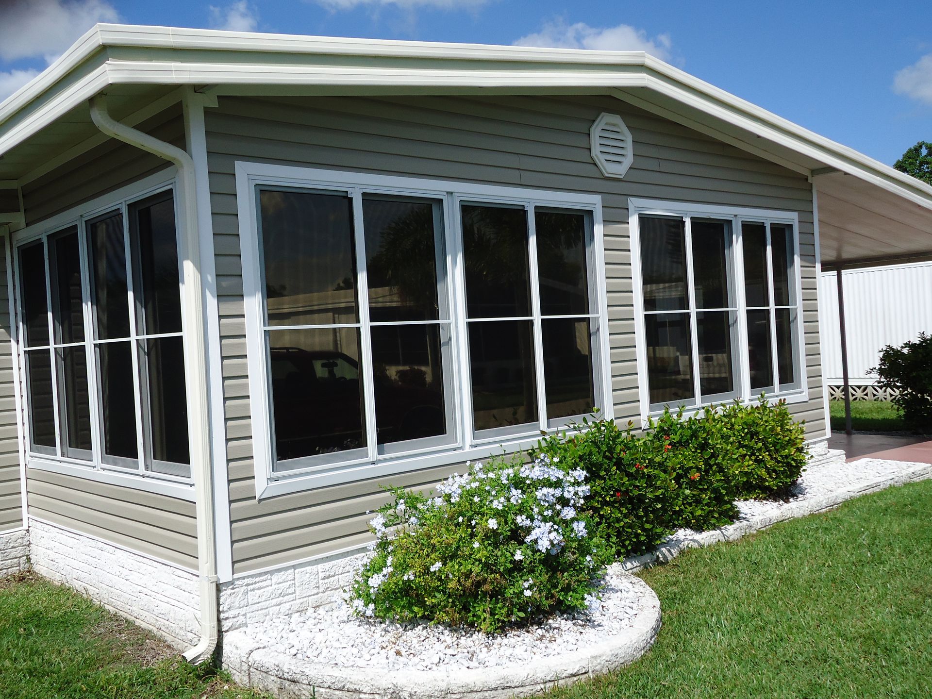 A mobile home with a screened in porch and lots of windows