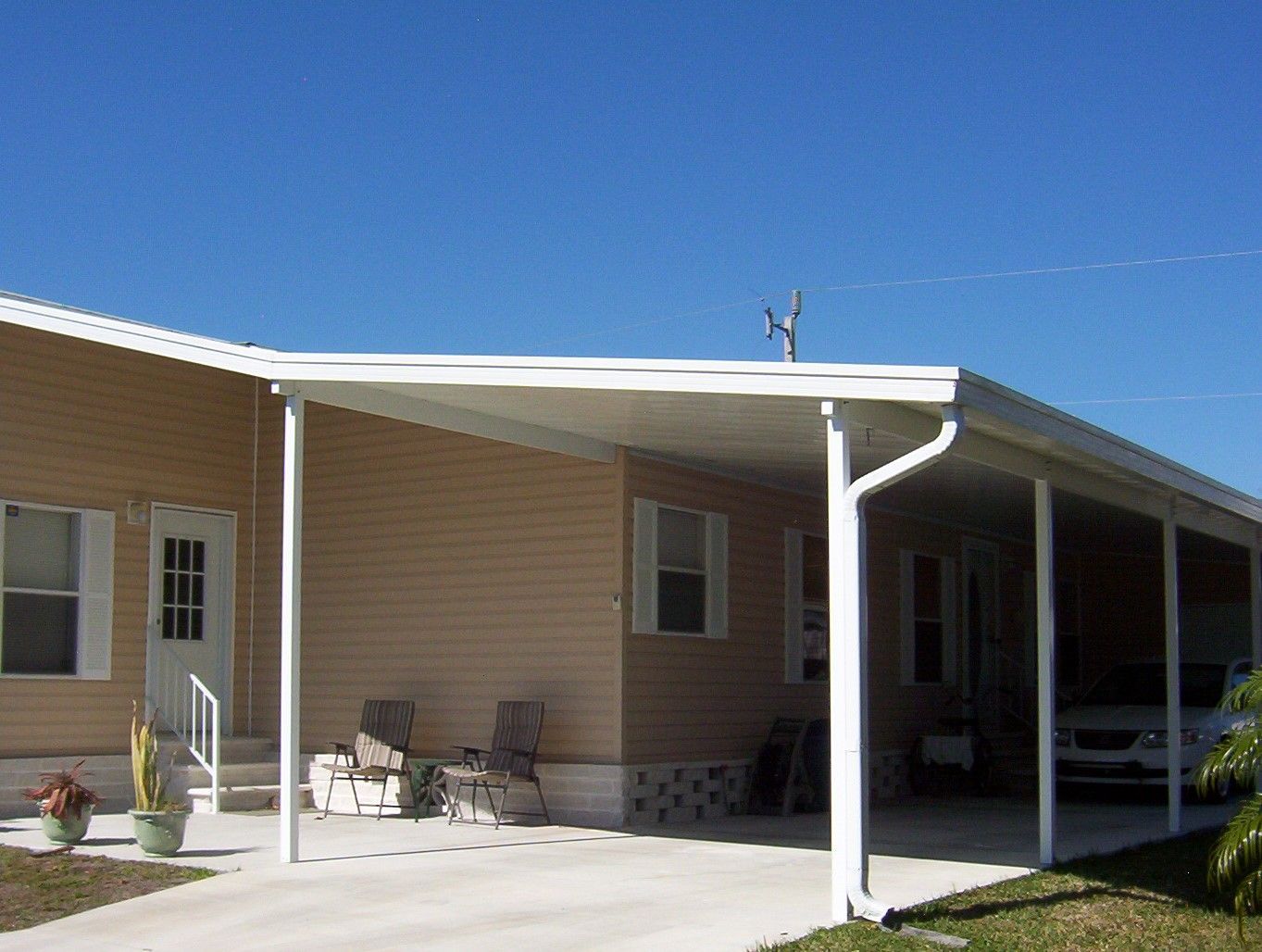 A house with a covered porch and a car parked underneath it