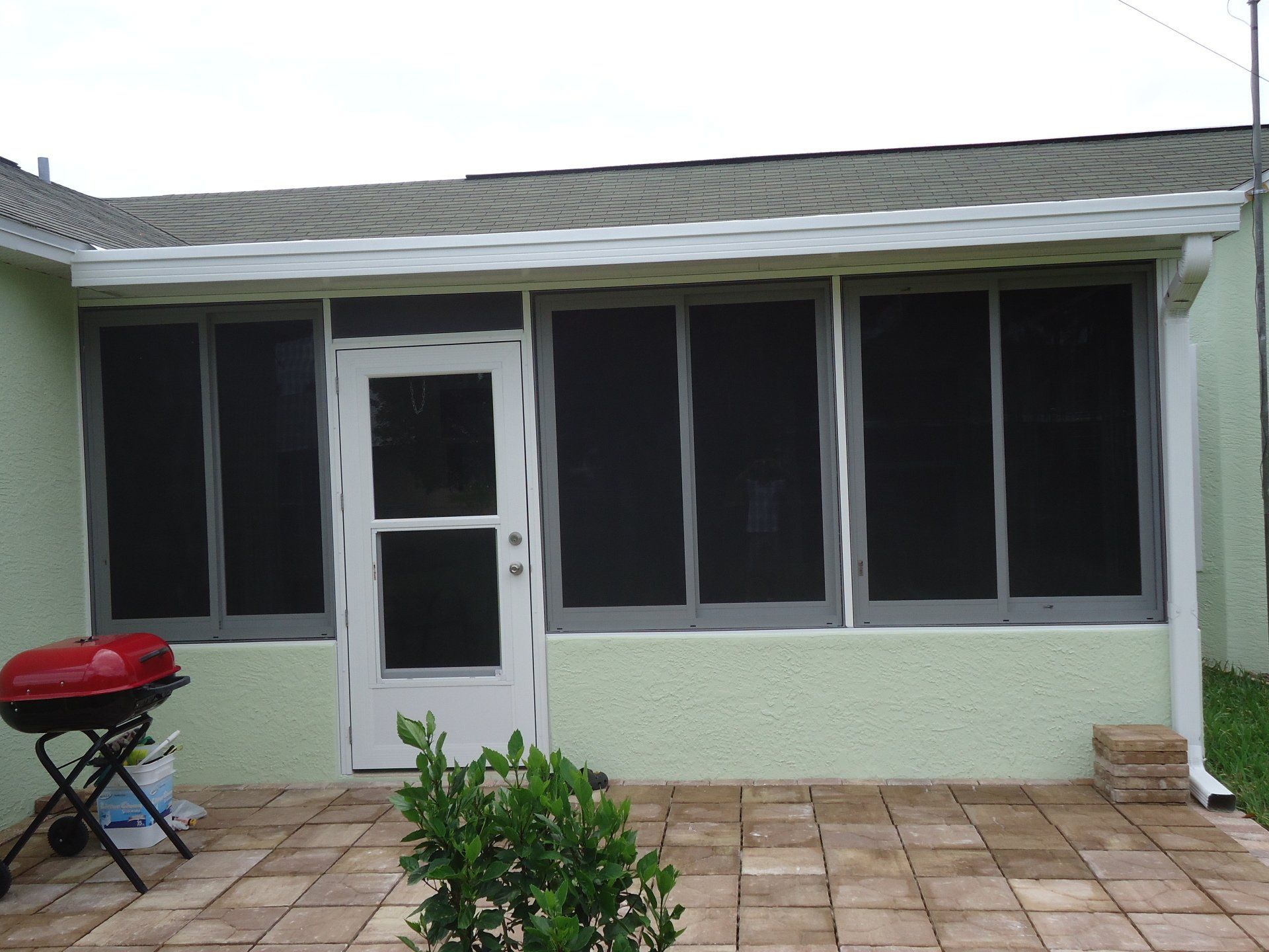 A screened in porch with a grill in front of it