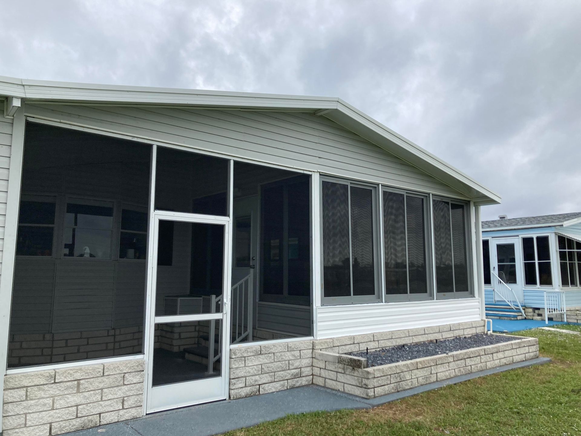A mobile home with a screened in porch and a pool.