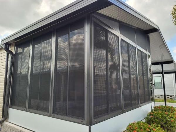 A screened in porch on the side of a mobile home.