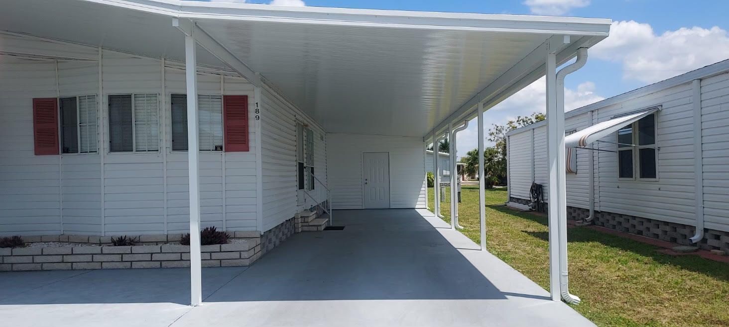 A white mobile home with a covered porch in front of it.