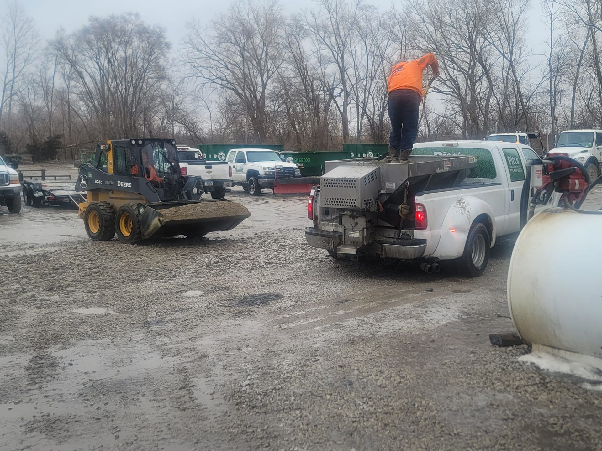 A man is standing on the back of a truck in a parking lot.