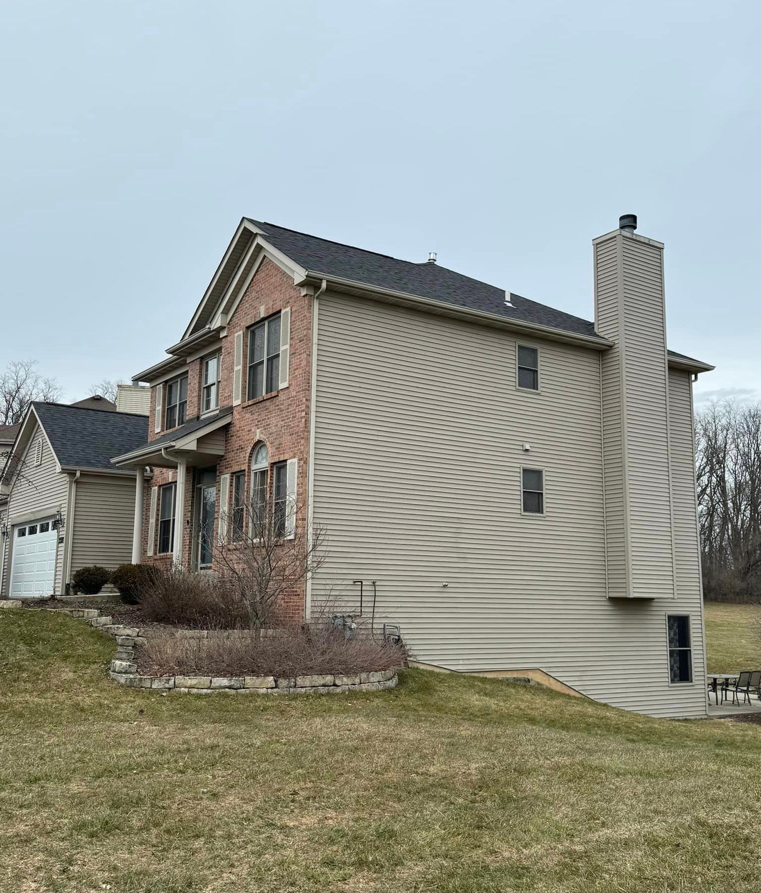 A large house with a brick roof is sitting in the middle of a grassy field