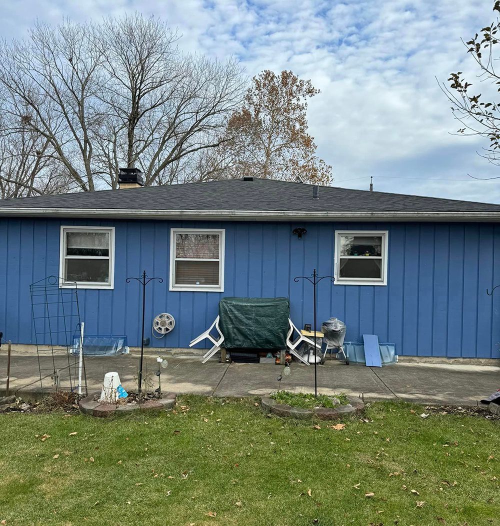 A blue house with a lot of windows and a patio in front of it