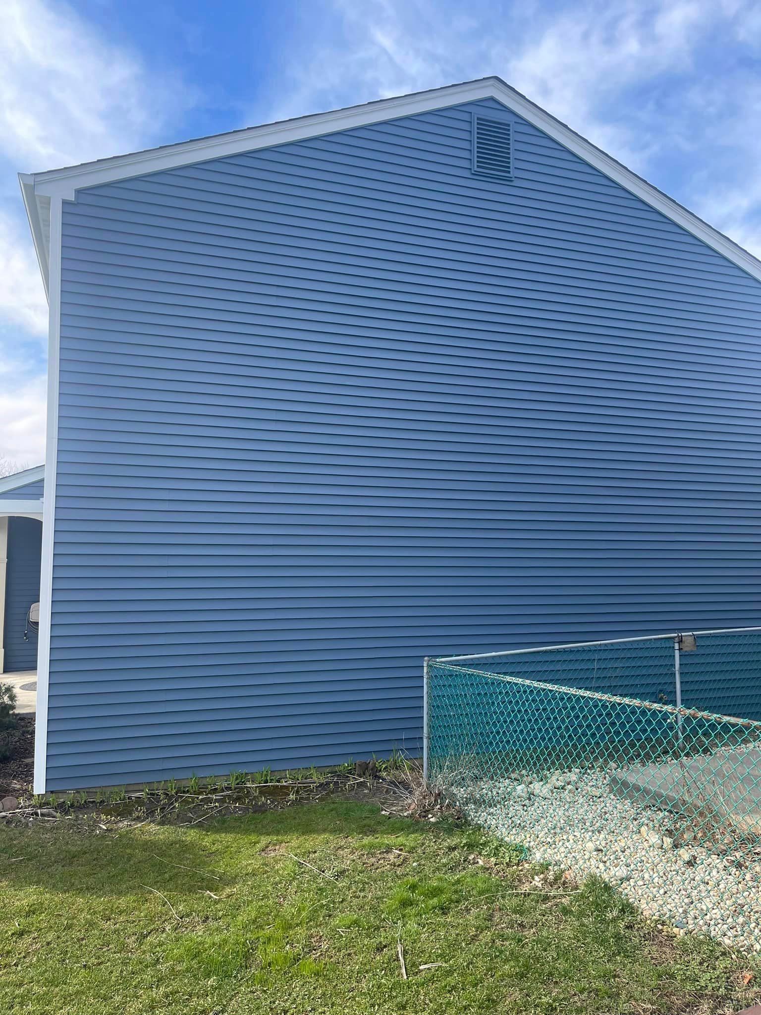 A blue house with a white trim and a fence in front of it