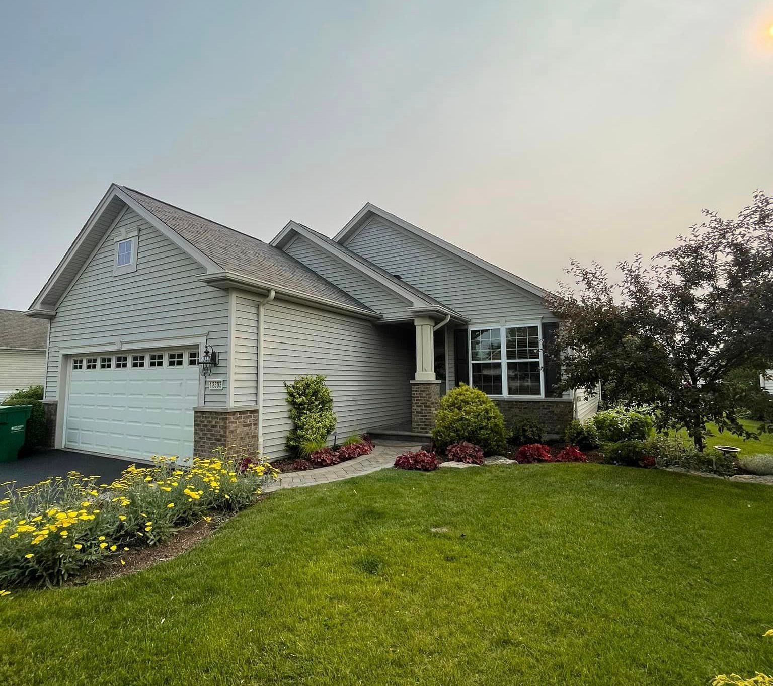 A white house with a white garage door is sitting on top of a lush green lawn