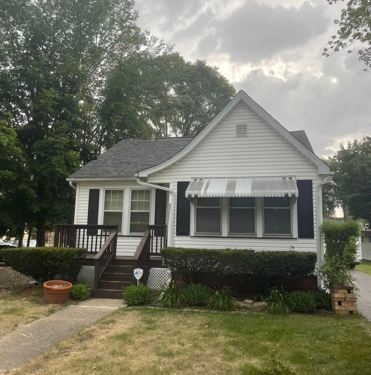A small white house with black shutters and a canopy