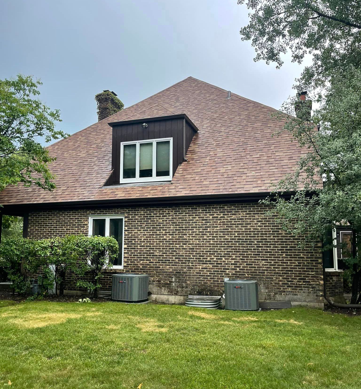 A brick house with a brown roof and a lot of windows