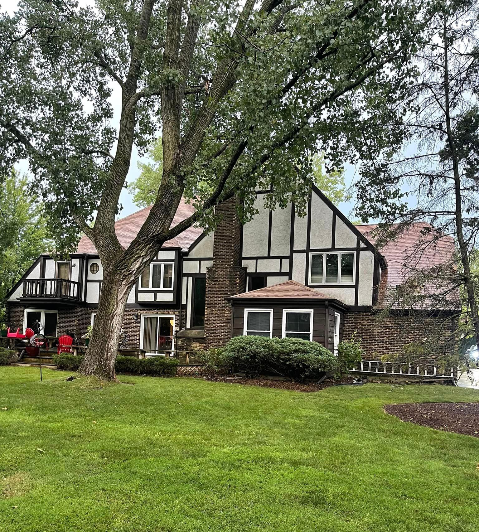 A large house with a large lawn in front of it surrounded by trees