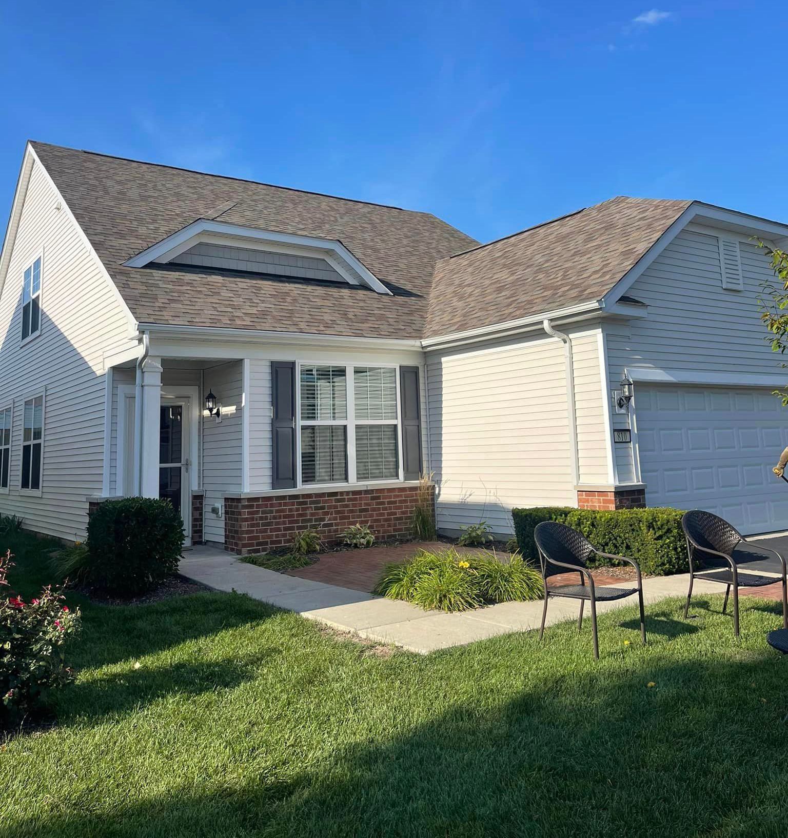 A white house with a brown roof and a lot of windows