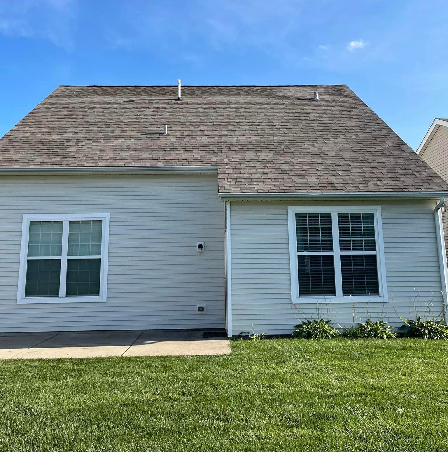 A white house with a brown roof and a lot of windows