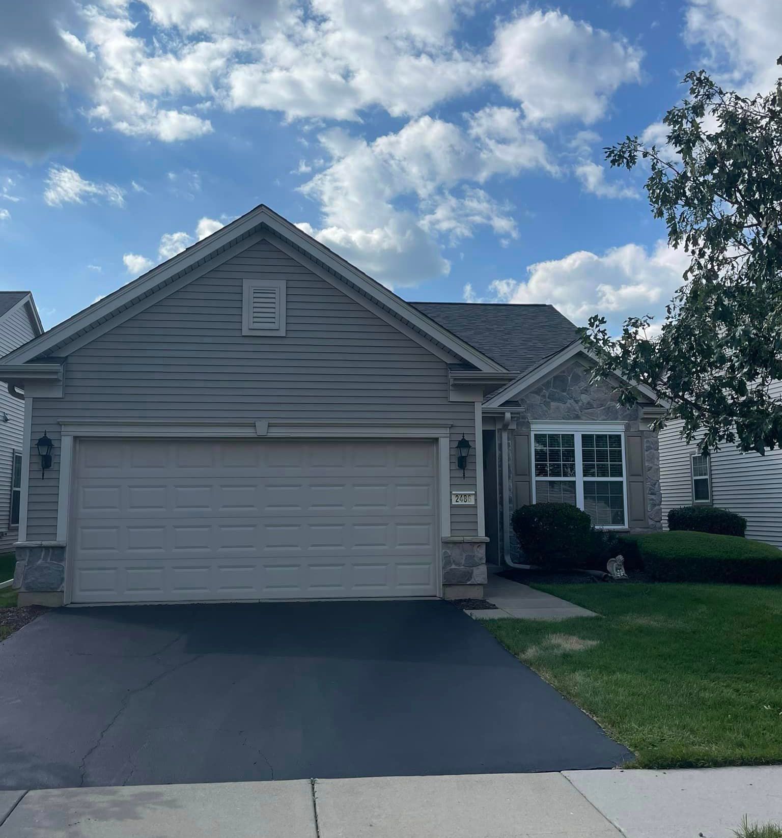 A gray house with a white garage door and a blue sky in the background