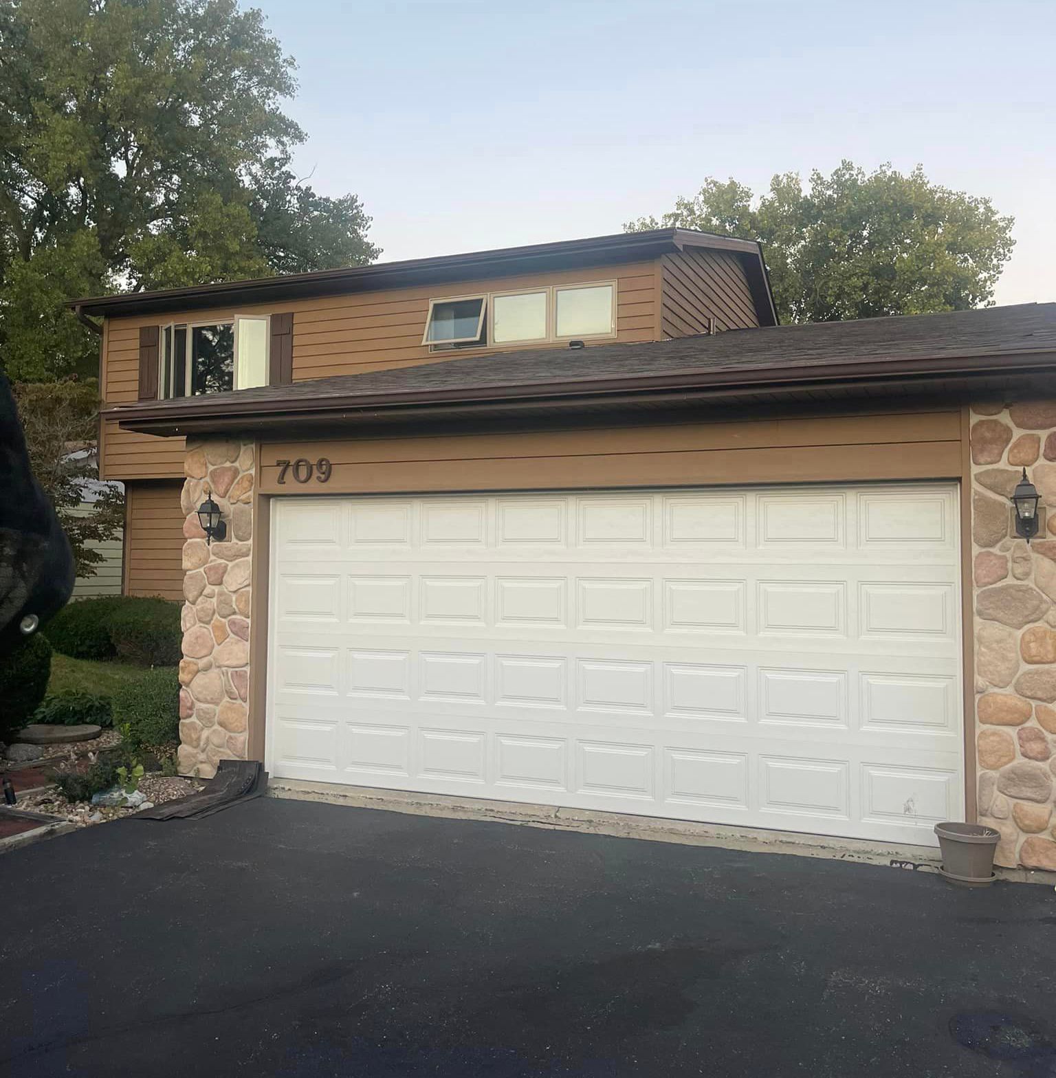 A house with a white garage door has the number 709 on it