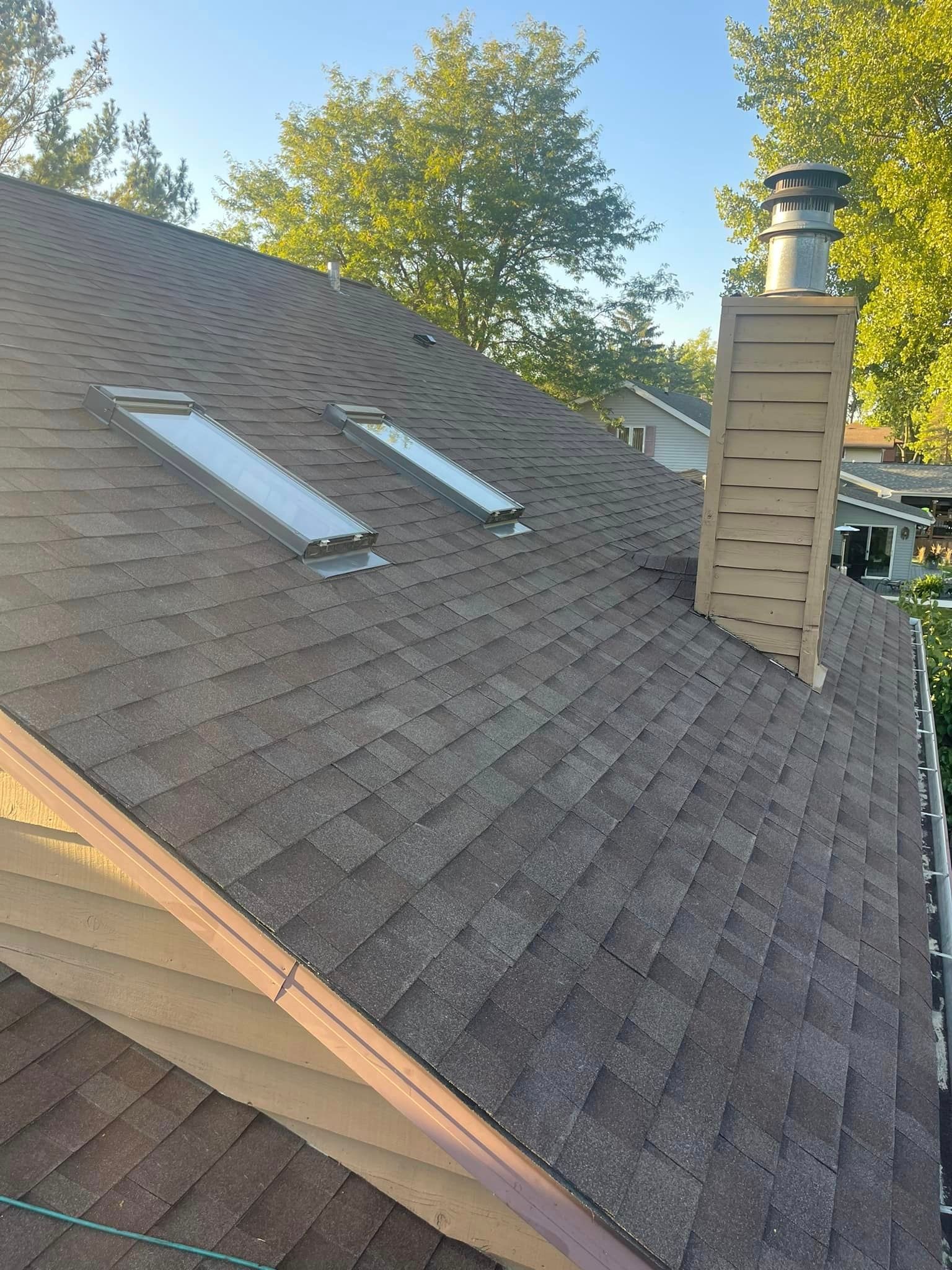 A roof with two skylights and a chimney on it