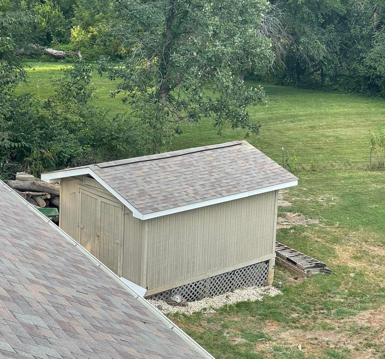 A small shed is sitting in the middle of a grassy field