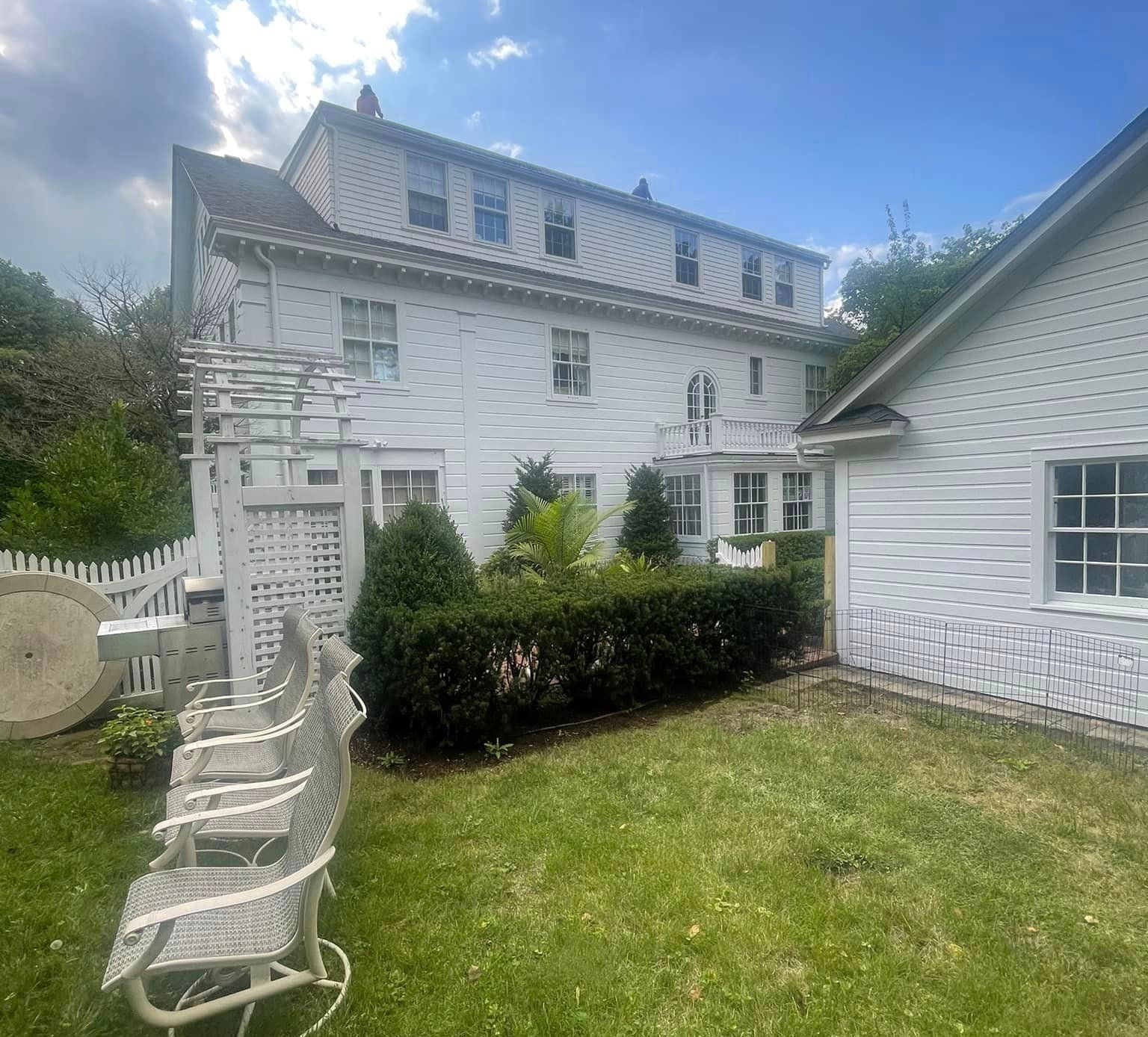A white house with a lawn and chairs in front of it