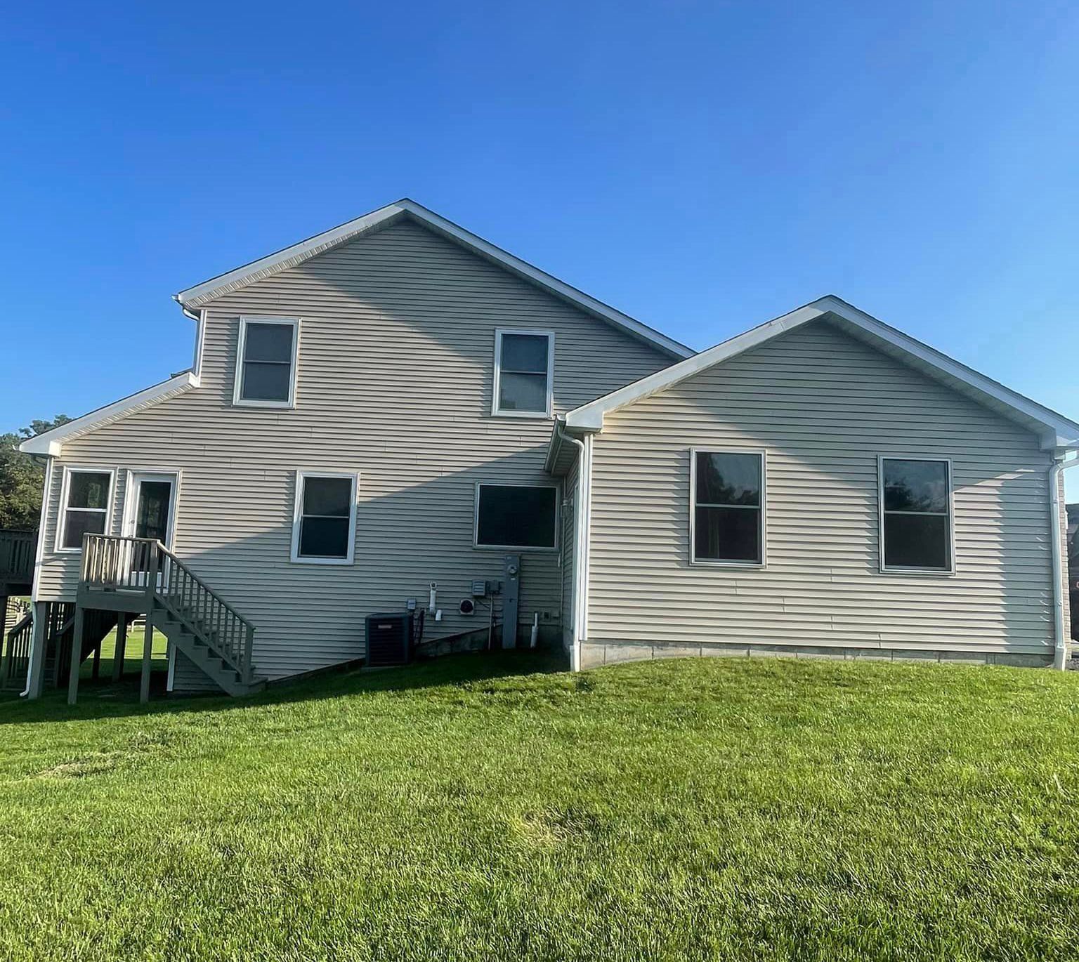 A large house with a lot of windows is sitting on top of a lush green field