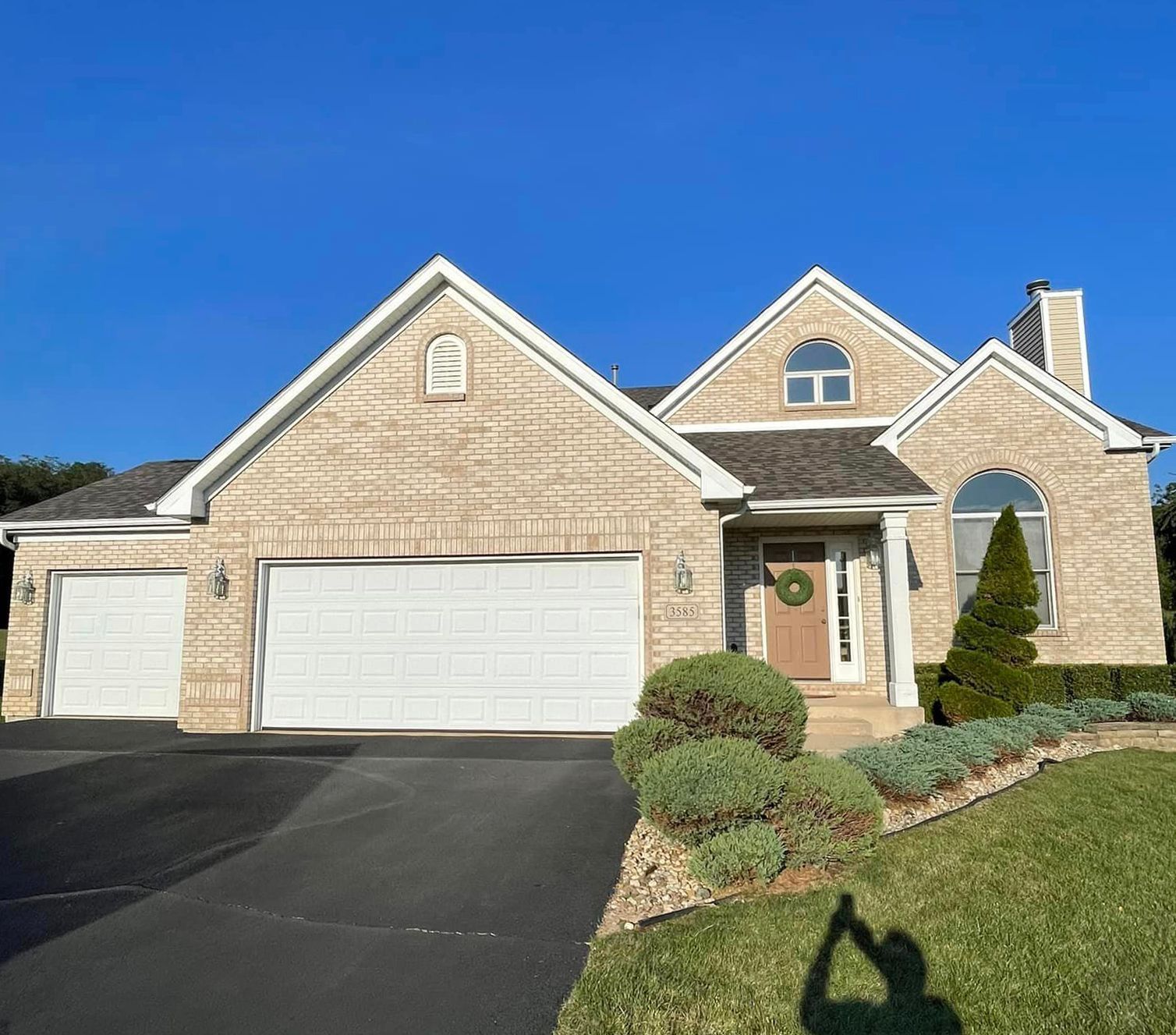 A large brick house with two garage doors and a wreath on the door
