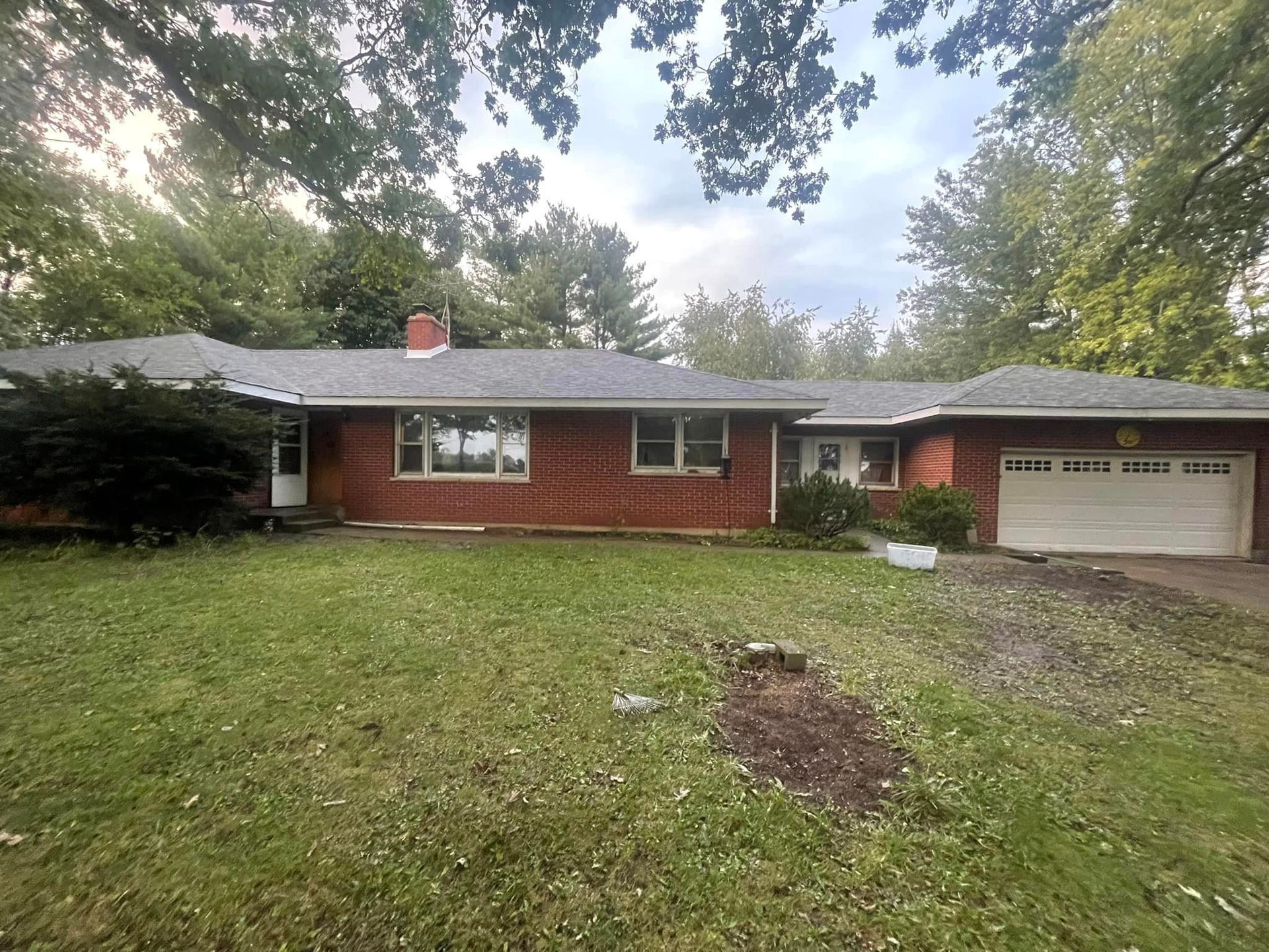 A brick house with a garage and a large lawn in front of it