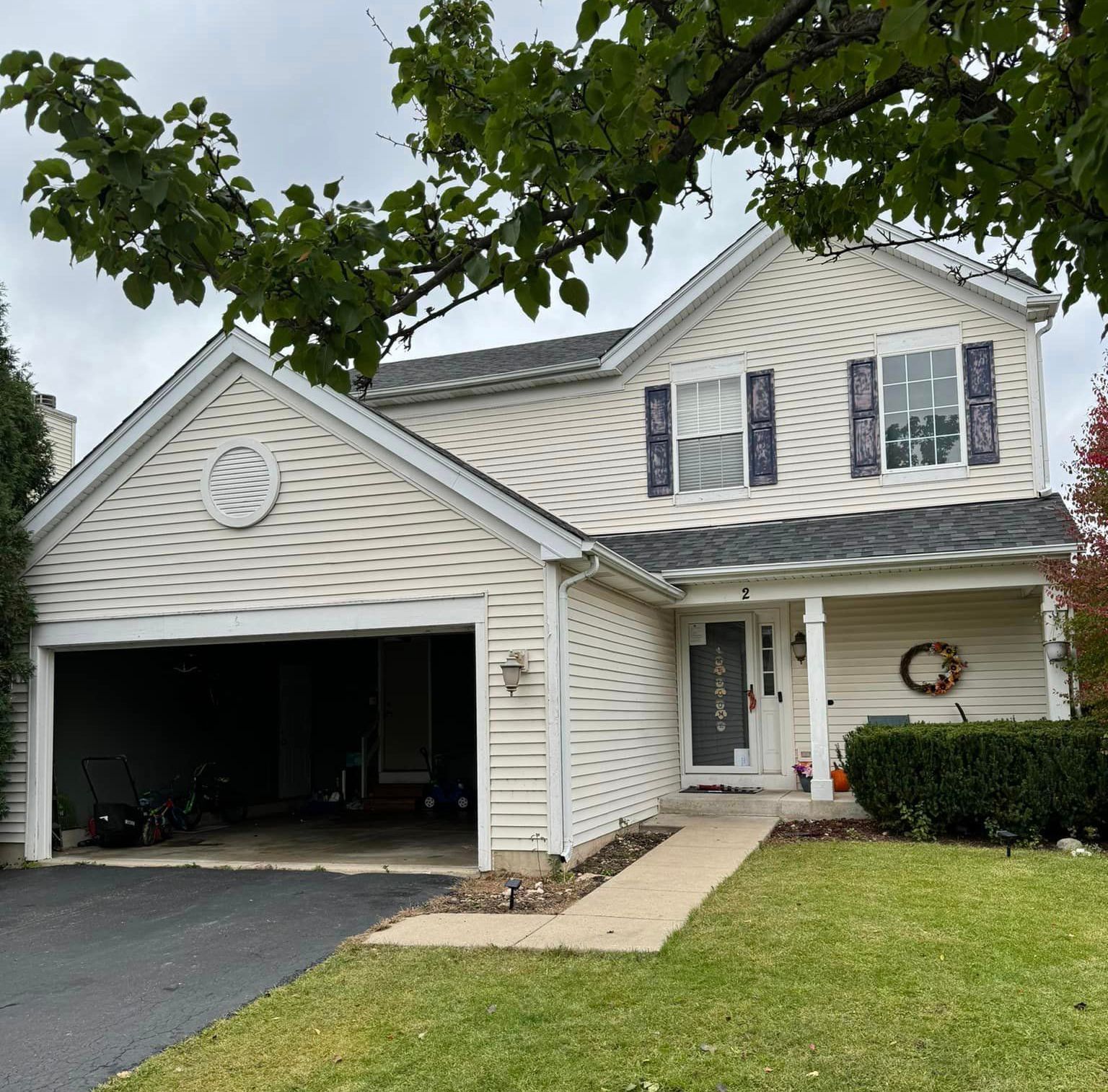 A white house with black shutters and a wreath on the front door