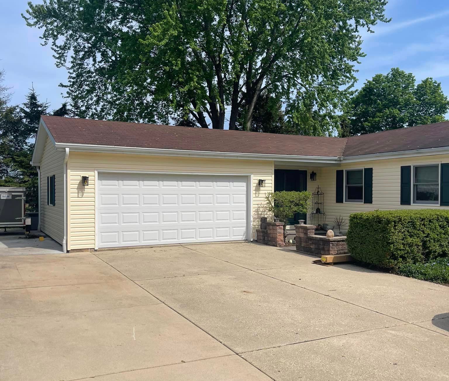 A house with a white garage door and a brown roof