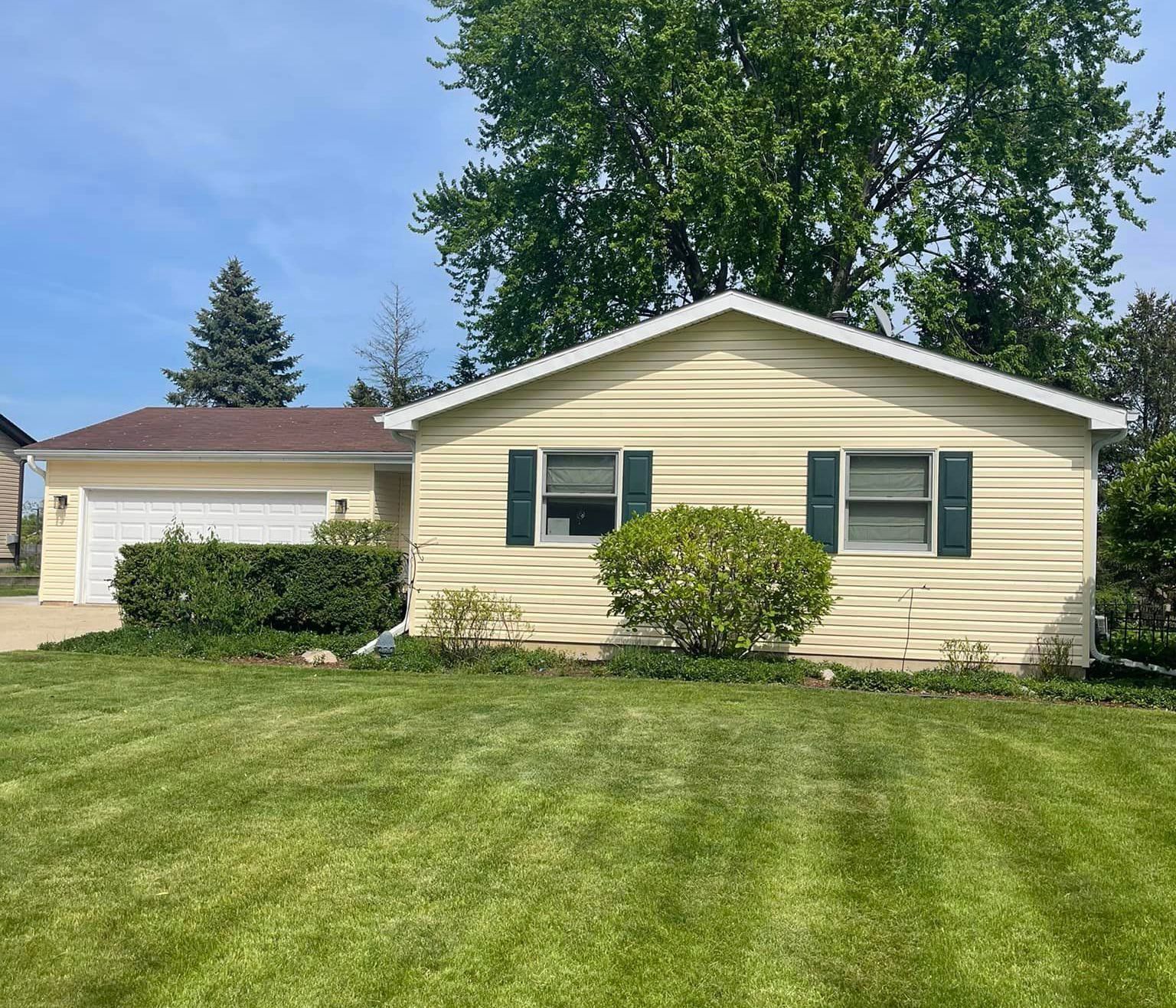 A small house with a large lawn in front of it