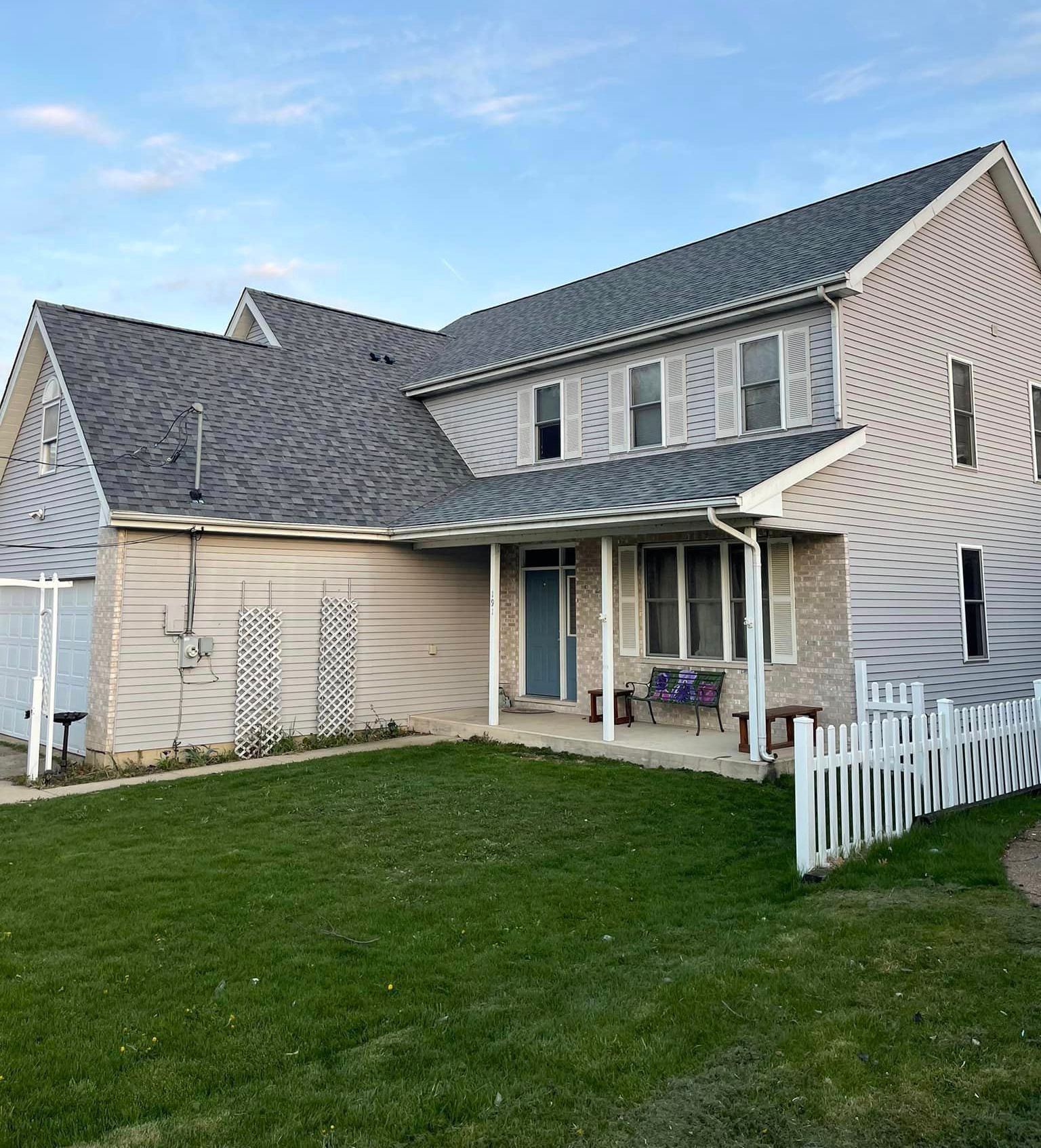 A large house with a porch and a white picket fence in front of it
