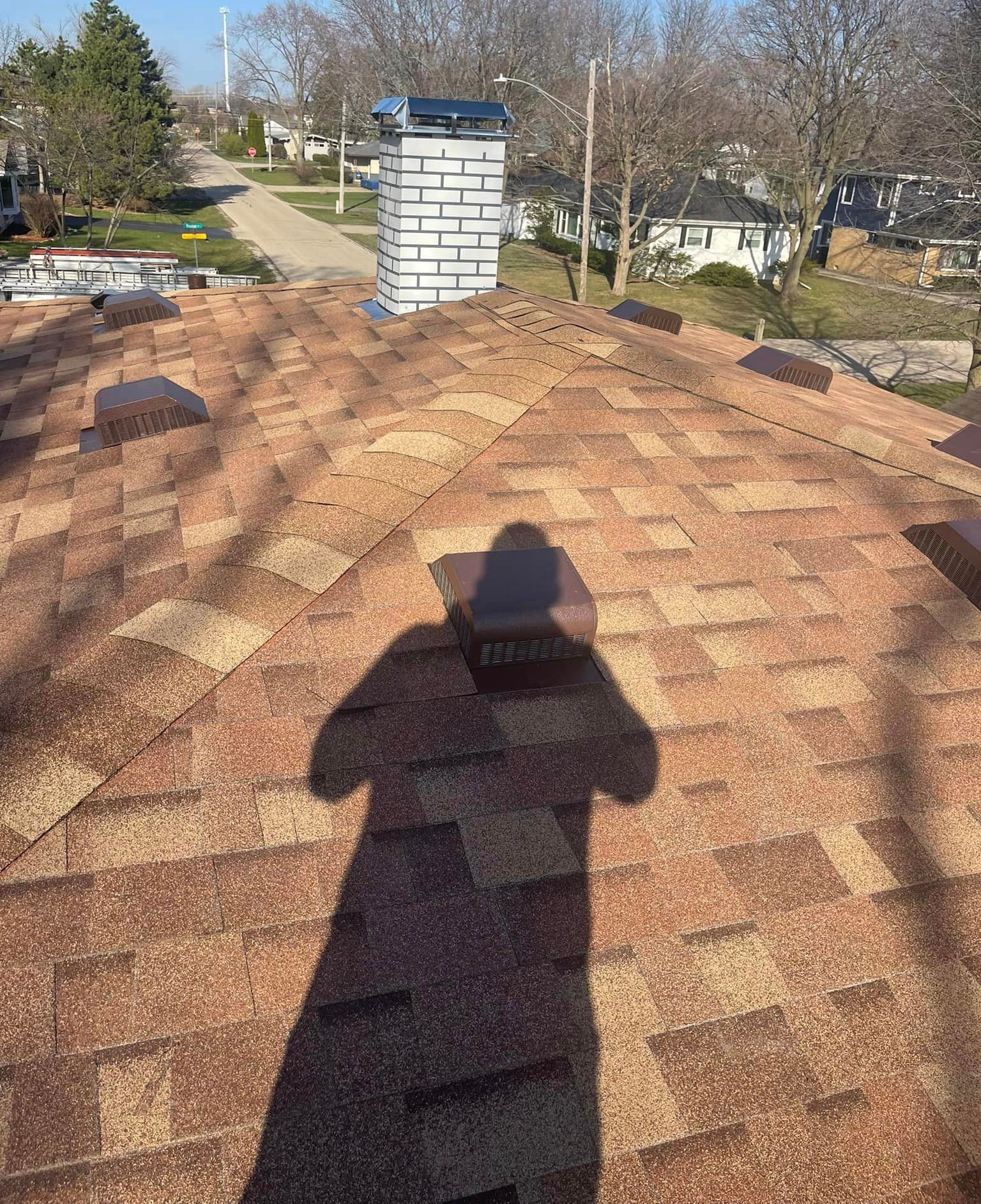A shadow of a person is cast on the roof of a house