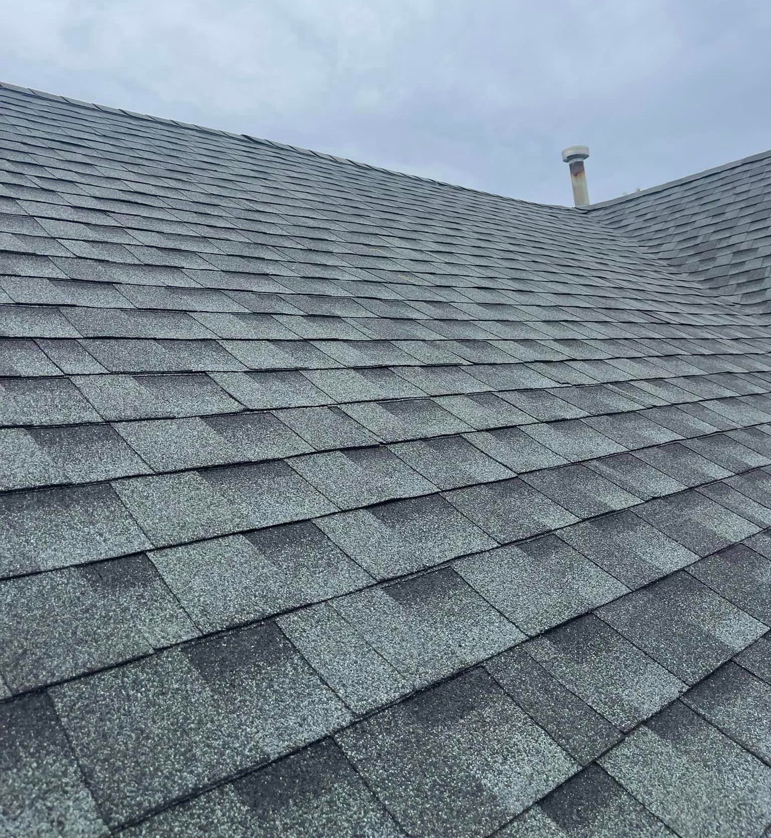 A close up of a roof with shingles and a chimney