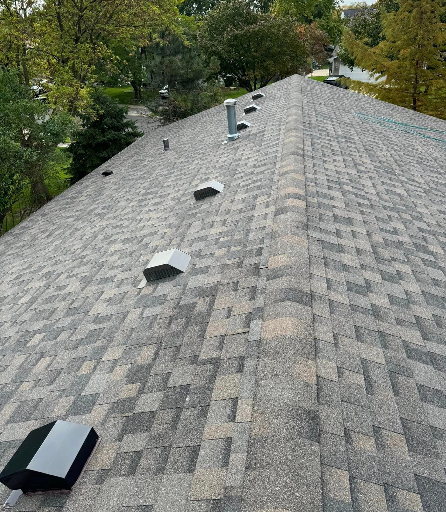 A roof with a lot of shingles on it and trees in the background