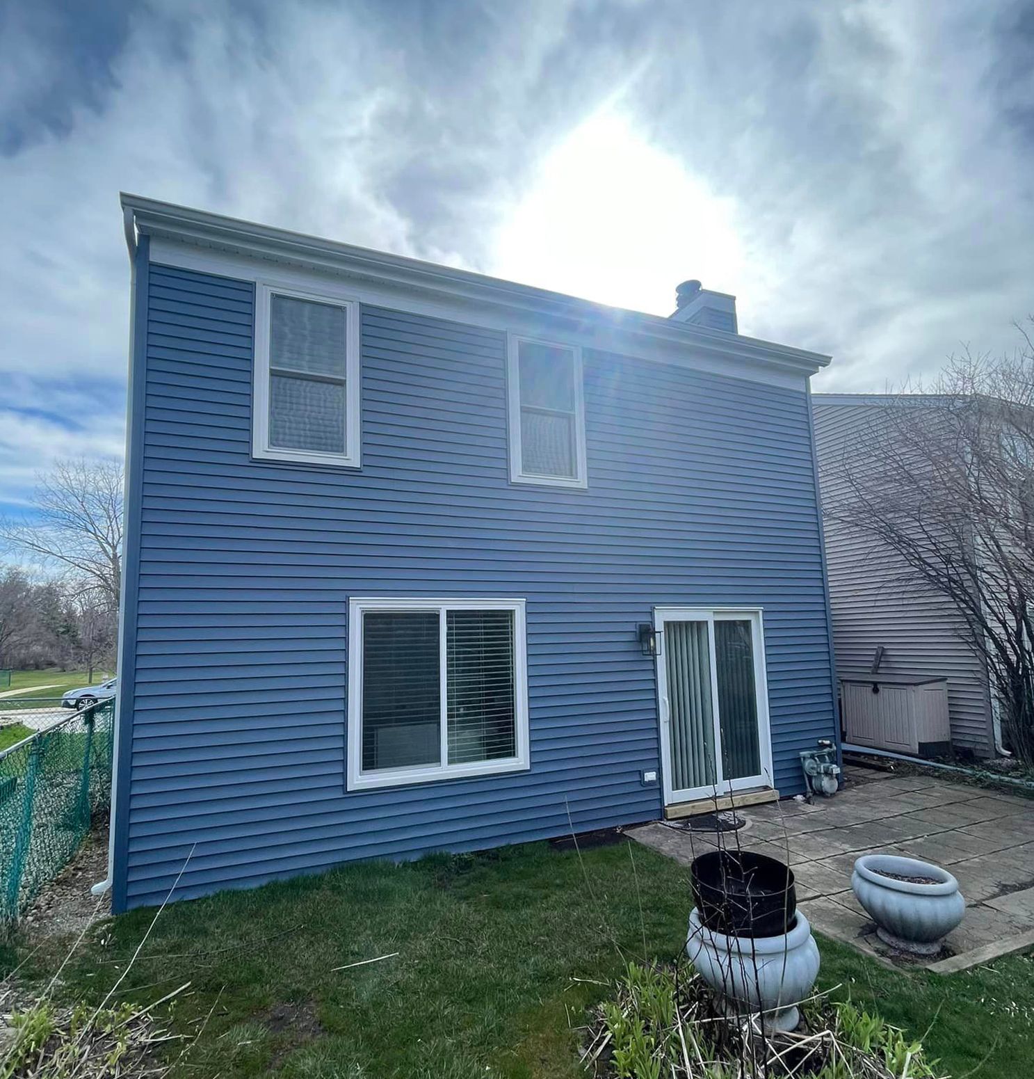 The back of a blue house with a lot of windows and a patio