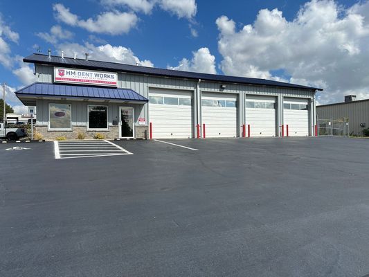 Gray commercial building with three garage doors and a sign for 