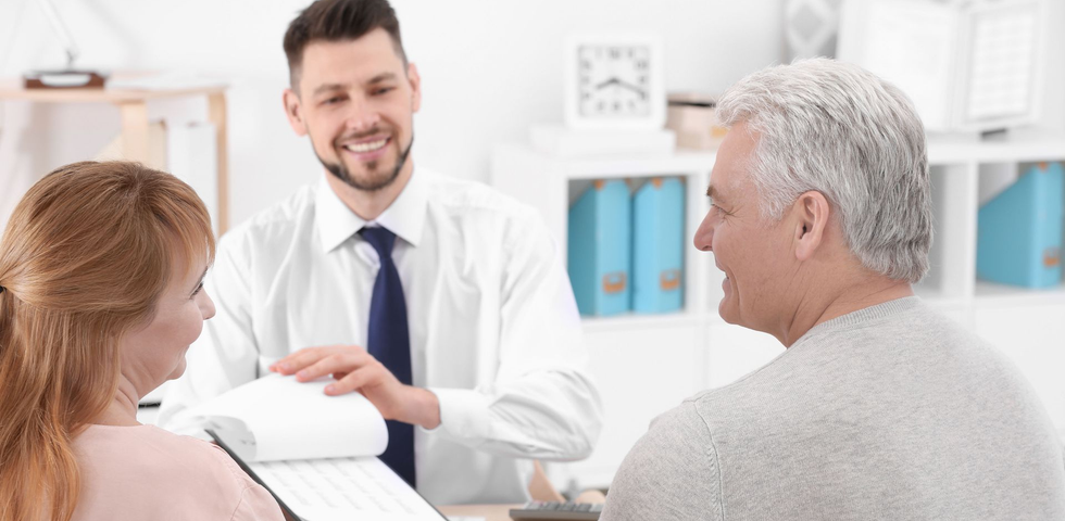 Doctor discussing paperwork with two seated patients in a bright clinic office