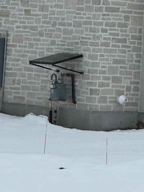 gas meter cover in front of a brick building.