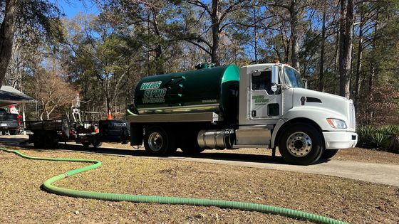 Learn more about drain lines White water truck with green tank parked on a gravel driveway in a wooded area