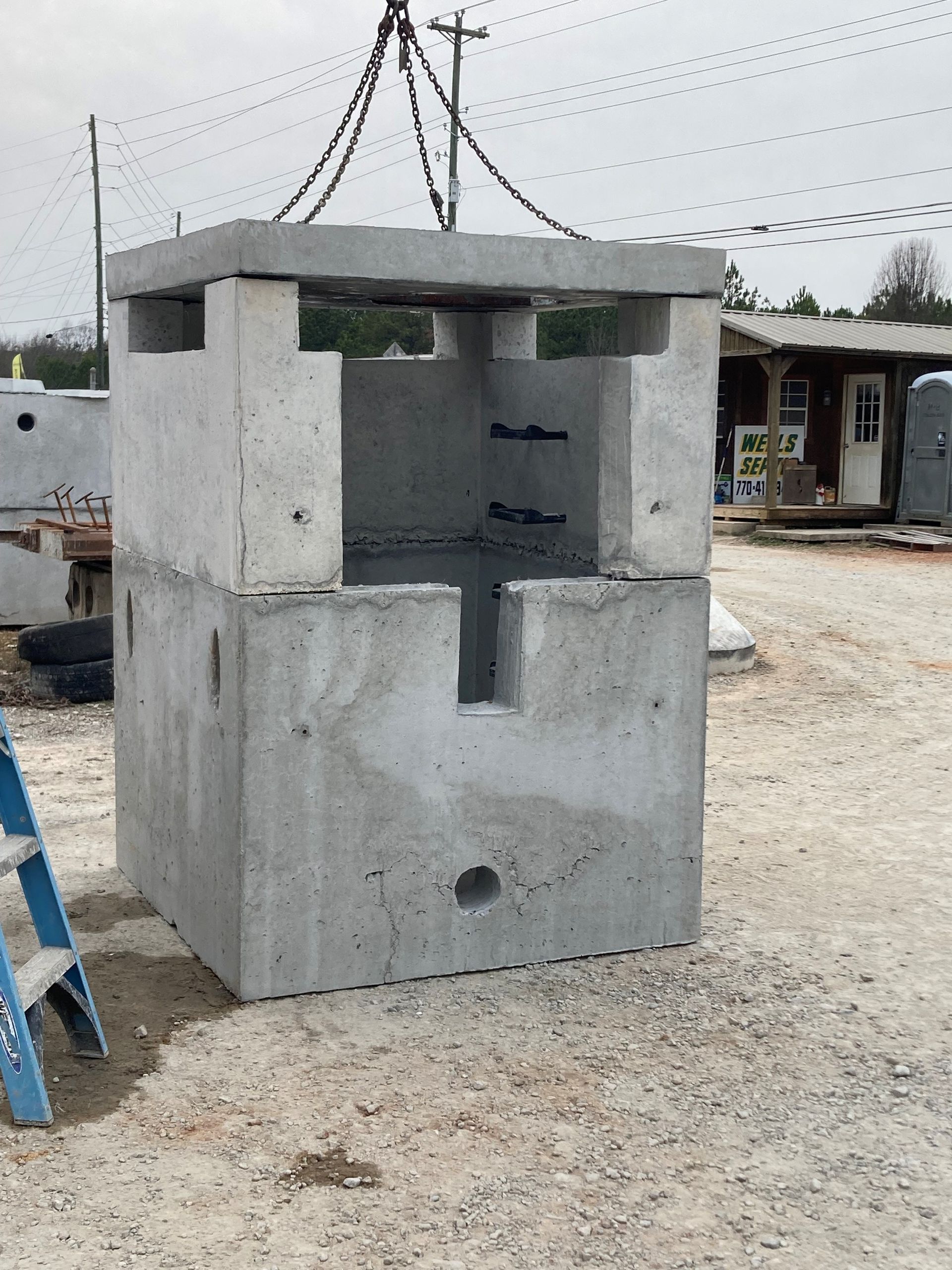 Gray concrete block structure being lifted at a construction site outdoors
