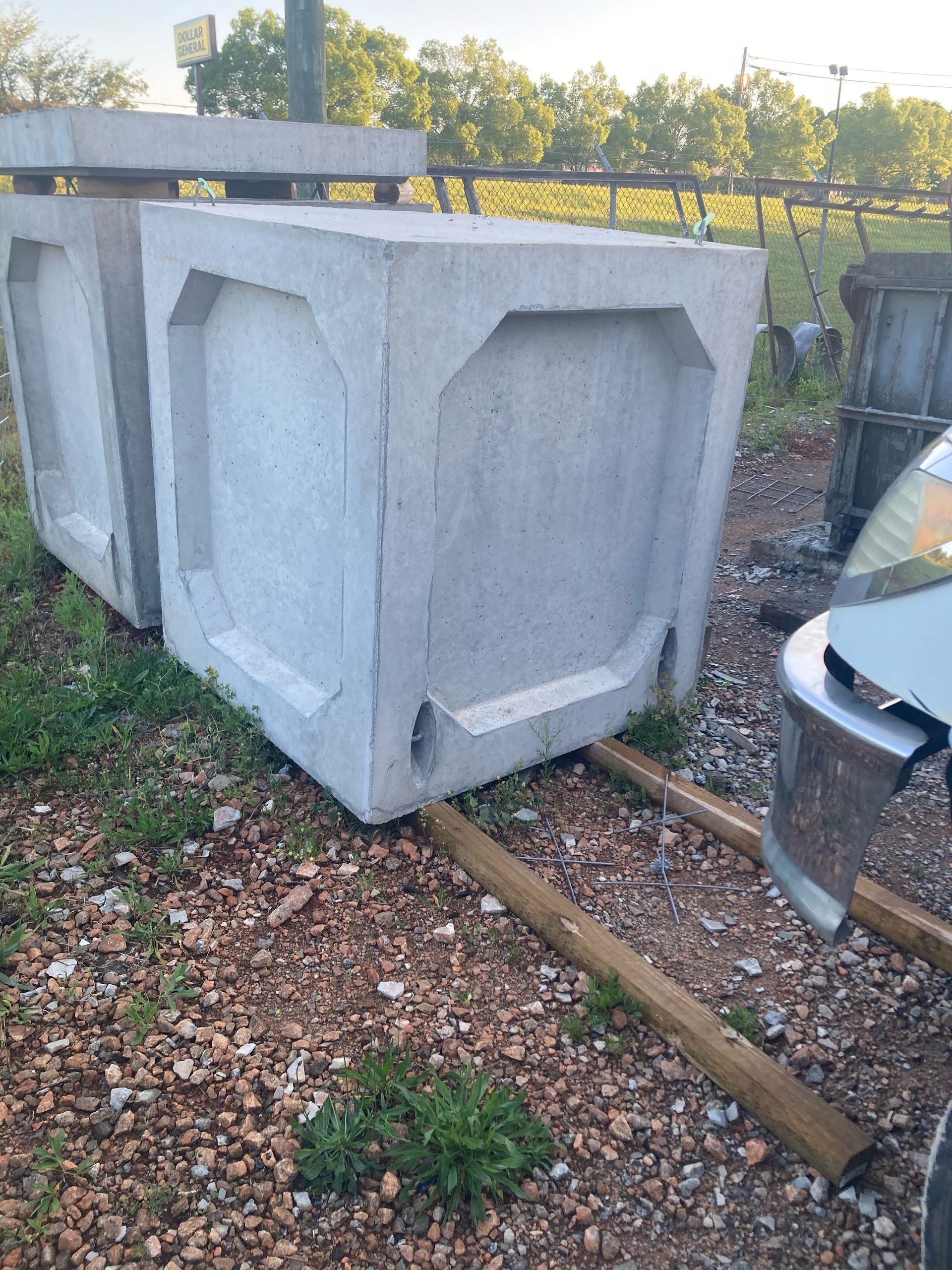 A concrete block is sitting on top of a pile of gravel next to a car