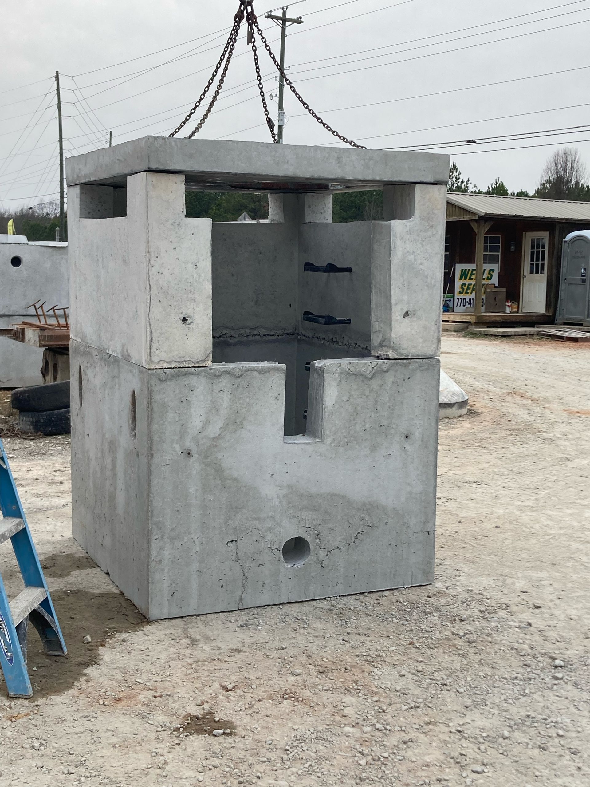 A blue ladder is sitting next to a large concrete block