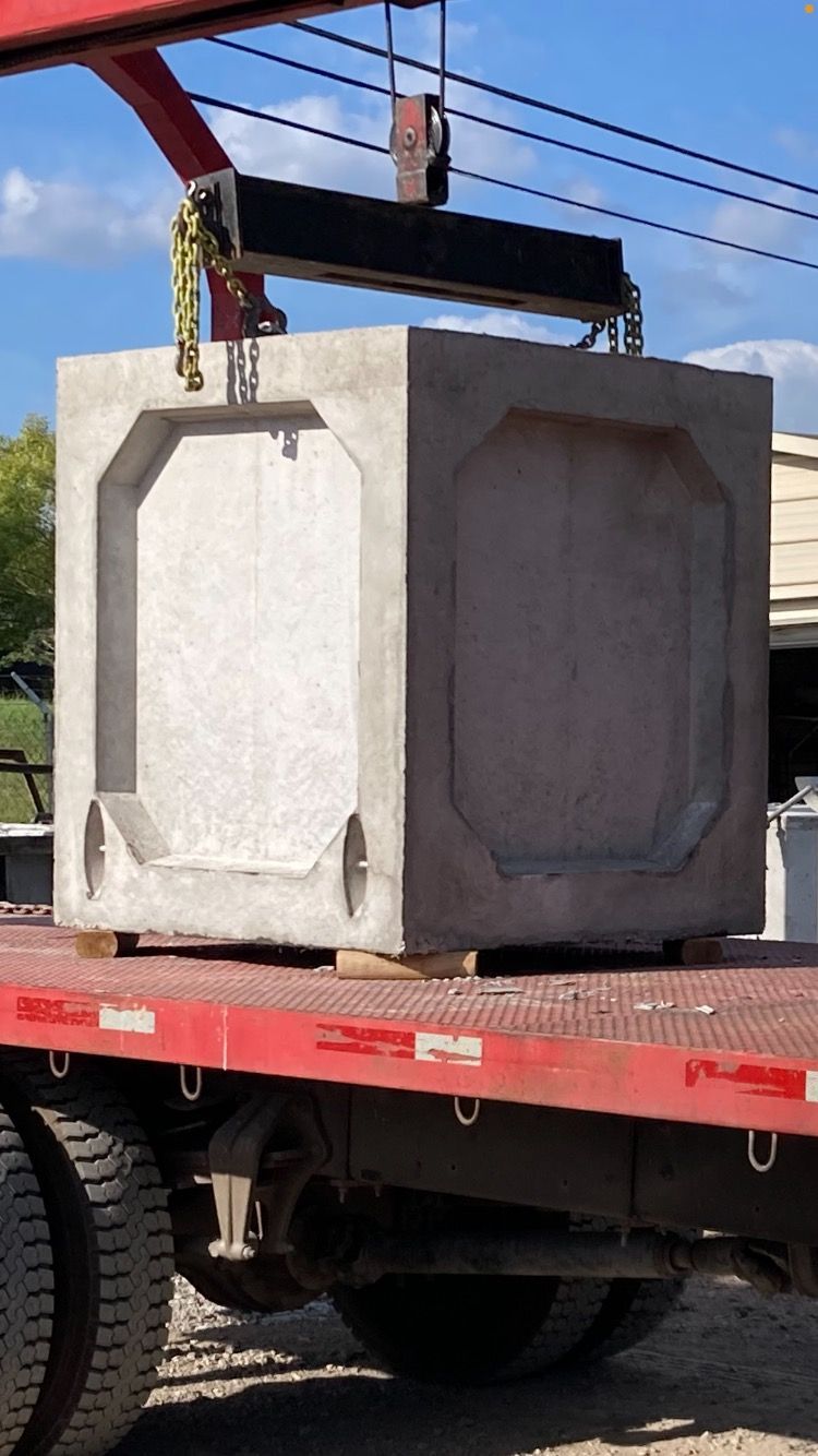 A large concrete block is being lifted by a crane on the back of a truck
