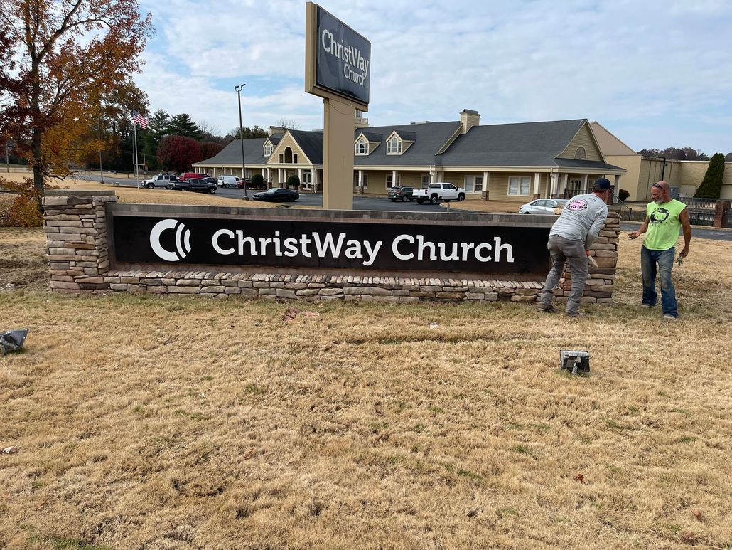 ChristWay Church sign with two people near it, church building in background.
