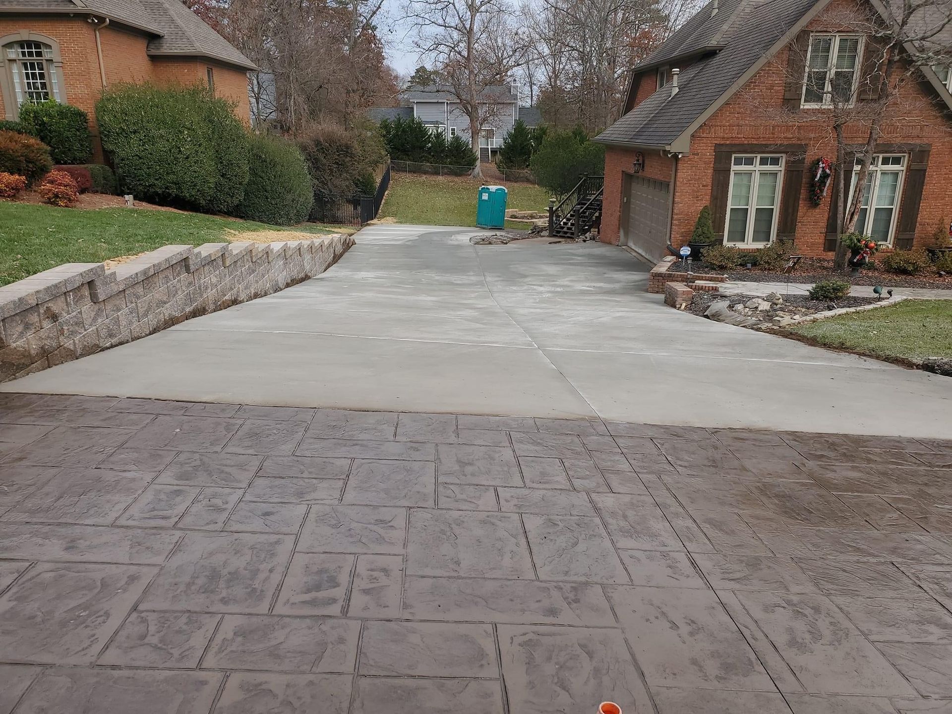 Driveway with stamped concrete leading to a house. A section of concrete is freshly poured.